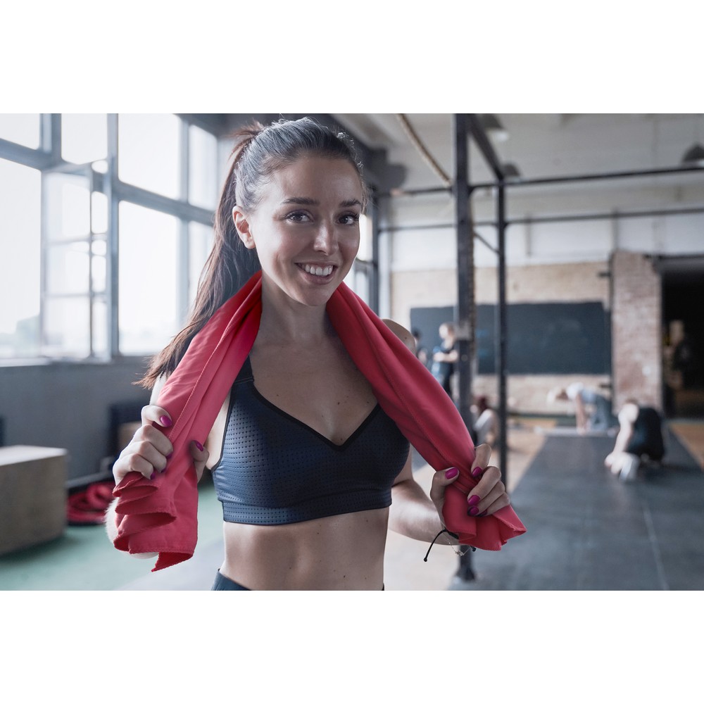 Woman with fit body standing at gym with towel around her neck